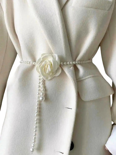 White coat with a decorative pearl belt with a white flower on a white background